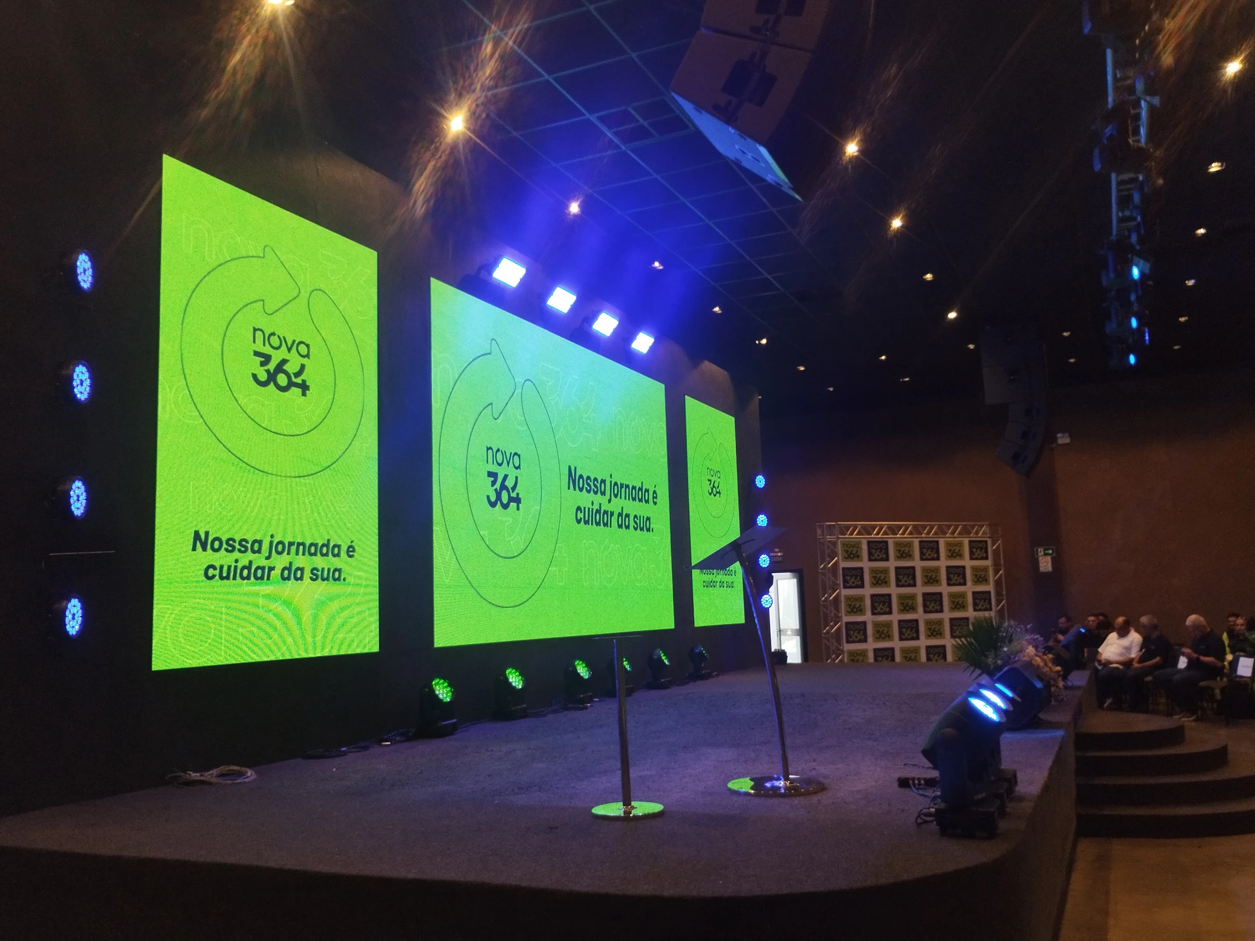 Auditório com palco, painel LED e plateia em evento corporativo